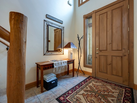 Step into your mountain retreat through this warm and welcoming entryway. Notice the thoughtful details—rustic wood tones, a cozy lamp for evening arrivals, and a spot to hang your gear after a day exploring the slopes.