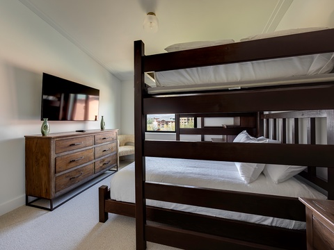Your family's perfect sleep setup awaits with crisp linens on the sturdy bunk bed, while the TV and dresser make this room feel like home away from home.