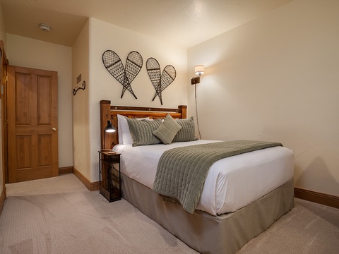 Curl up in crisp linens and cozy textures beneath vintage snowshoe décor. Your peaceful mountain retreat awaits, inviting restful nights in a thoughtfully designed space.