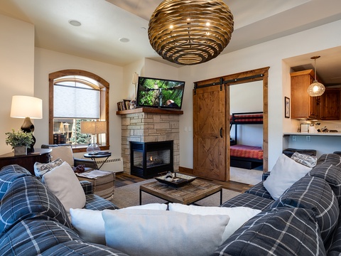 Unwind in your welcoming living area, where plush plaid sofas, a cozy fireplace, and a unique statement chandelier create the perfect mountain retreat ambiance for your stay.