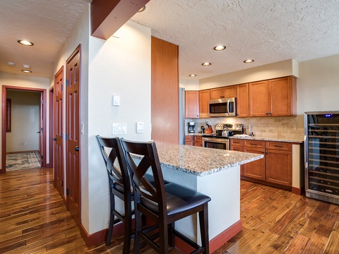 Your fully-equipped kitchen features warm wood cabinetry, granite countertops, stainless appliances, and a breakfast bar perfect for morning coffee or casual meals together.
