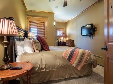 Your cozy bedroom features warm wood accents, plush bedding with colorful throws, and charming lamps that create a restful, inviting retreat for unwinding after adventure.