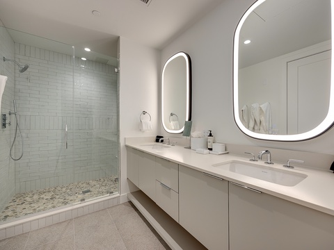 Step into your spa-inspired sanctuary with a spacious walk-in shower, dual vanities with backlit mirrors, and plush towels awaiting your arrival.