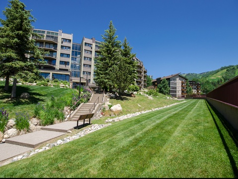 Modern property building nestled in a scenic mountain setting with lush green hillsides and manicured lawns, creating an inviting base for your stay.