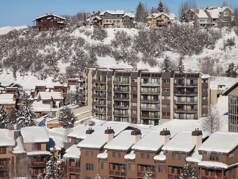 Snow-covered mountain resort community featuring multi-story lodges and chalets nestled among frosted evergreens, offering convenient access to winter slopes and alpine recreation.