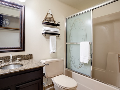 Your private bathroom features granite countertops, a walk-in shower with frosted glass doors, and plush towels for your comfort and convenience.
