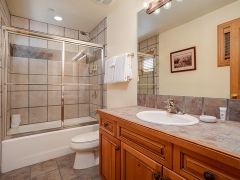Step into your private bathroom featuring warm wood cabinetry, tile details, and a tub-shower combo perfect for unwinding after a day of adventure.