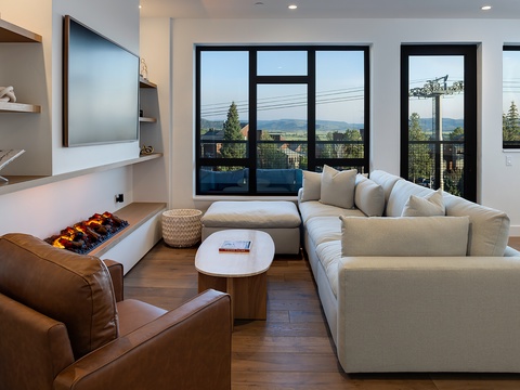 Sink into plush seating in your bright living room, where floor-to-ceiling windows frame breathtaking mountain views. The cozy fireplace adds warmth, while thoughtful details create a welcoming retreat for your mountain getaway.