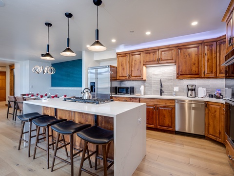 Gather around the spacious island in your gourmet kitchen, featuring warm wood cabinetry, sleek stainless appliances, and a gas cooktop—perfect for preparing meals together and creating lasting memories.