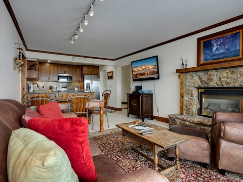 Unwind in your spacious living area featuring a cozy stone fireplace, leather seating, and a fully equipped kitchen—your perfect mountain retreat awaits.