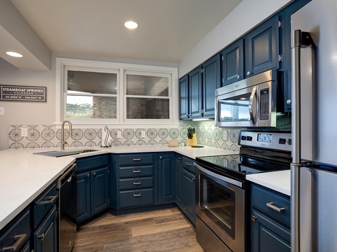 Your gourmet kitchen features elegant navy cabinetry, gleaming stainless appliances, and stylish patterned tile. Picture yourself cooking meals with ample counter space and modern conveniences at your fingertips.