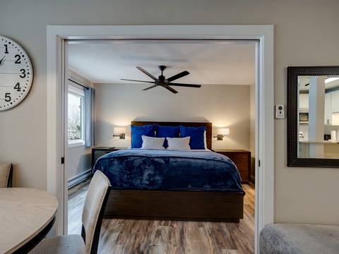 Step into your serene bedroom retreat with plush bedding, warm lighting, and a ceiling fan to keep you cool—your restful night awaits in this inviting space.