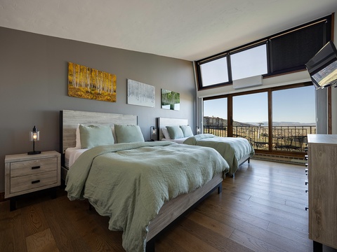 Drift off in this serene bedroom with two plush beds, warm hardwood floors, and stunning panoramic views that greet you each morning through floor-to-ceiling windows.