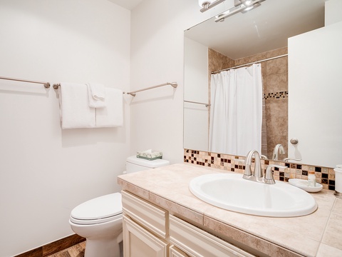 Your private bathroom features a crisp white vanity, decorative tile accents, and plush towels—clean, comfortable, and ready for a refreshing start to your day.