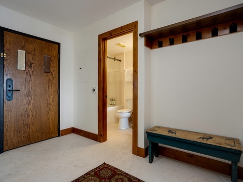 This charming entryway greets you with rustic wood accents and a cozy bench—perfect for settling in after a day of exploring. A gleaming bathroom awaits just steps away.