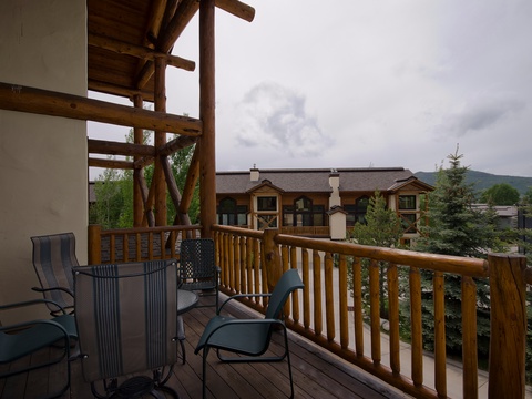 A spacious covered deck with seating for dining and relaxing overlooks nearby mountain views and evergreens, creating an ideal retreat for outdoor moments.