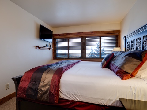 Sink into this plush bed and wake to natural light filtering through wooden blinds. Your private flat-screen TV and stylish accents create a restful mountain retreat.