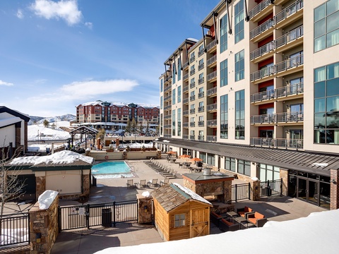 A spacious ski resort complex featuring heated outdoor pool, hot tub, fire pit lounge, and mountain views—perfect for après-ski relaxation.