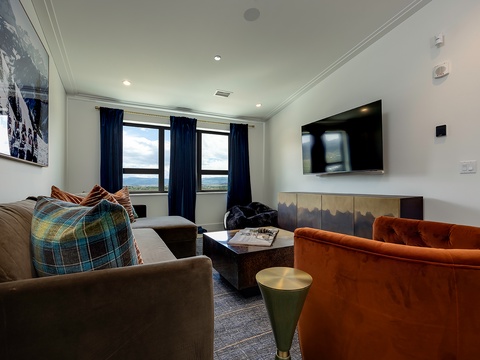 Unwind in your stylish living space with comfortable seating and stunning mountain views framing the windows—perfect for relaxing after a day of adventure.