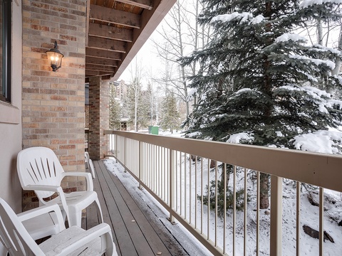 Snow-dusted balcony overlooks a serene winter wonderland, where towering evergreens frame a peaceful alpine retreat.