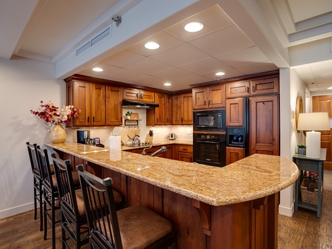 Your gourmet kitchen features rich wood cabinetry, gleaming granite countertops, and modern appliances—perfect for preparing meals and gathering with loved ones over the spacious breakfast bar.