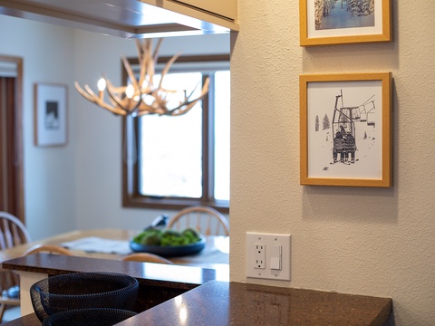 Step inside your mountain getaway with rustic charm—an antler chandelier hangs above your dining area, while ski-themed artwork hints at adventures nearby.