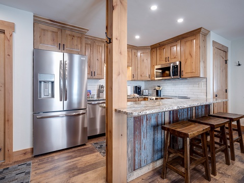 This inviting kitchen blends rustic charm with modern convenience, featuring warm wood cabinetry, stainless steel appliances, and a stunning reclaimed-metal island with seating perfect for your morning coffee.