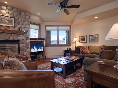 Unwind in your cozy mountain retreat where rich leather seating and a stone fireplace welcome you home after a day of adventure, with stunning views framing every moment.