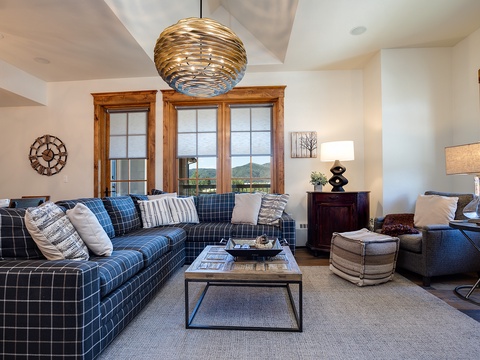 Sink into the plush plaid sofa and unwind beneath a stunning sculptural pendant. Your cozy retreat features warm wood accents, mountain views, and inviting seating—perfect for relaxing evenings together.
