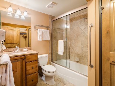 Step into a beautifully appointed bathroom with warm wood tones, gleaming fixtures, and fresh linens waiting for you. Soak in the tub-shower combo after your mountain adventures.
