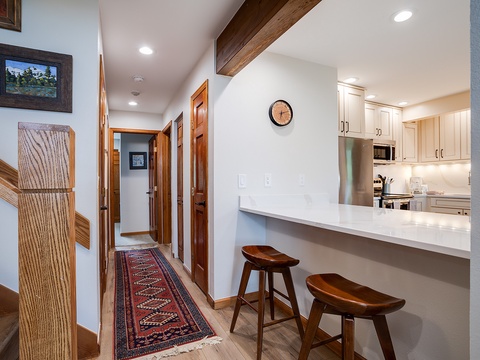 Step into your mountain getaway where rustic wood beams and a bright, open kitchen create the perfect home base. Slide onto the bar stools for morning coffee or grab a quick snack between adventures.