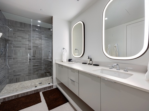 Step into your serene spa-like bathroom, where soft lighting frames sleek mirrors and a spacious walk-in shower invites you to unwind after a day of exploring.