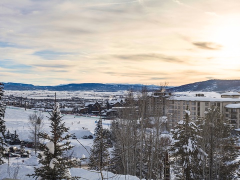A stunning winter vista showcasing snow-covered mountains, valley expanses, and the surrounding resort area blanketed in crisp white snow beneath a serene sky.