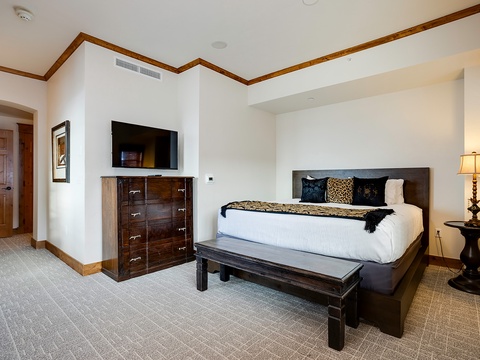 Sink into your plush bed after a day of adventure. Dark wood accents and warm lighting create a restful sanctuary where you'll unwind in comfort and style.