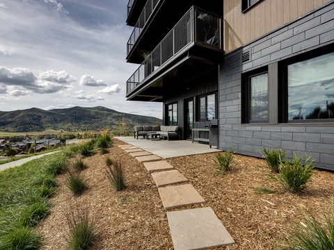 Modern mountain retreat featuring thoughtfully landscaped grounds with native plantings, a sleek patio, and stunning vistas of the surrounding valley and peaks.
