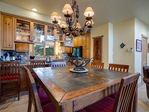 Gather around this handsome dining table under a stunning wrought-iron chandelier. The adjoining open kitchen invites you to whip up meals while staying connected with your group.