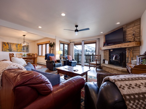 Settle into plush leather seating by the wood-burning fireplace as natural light floods through windows framing stunning mountain vistas. Warm woods and cozy textures create your perfect alpine retreat.