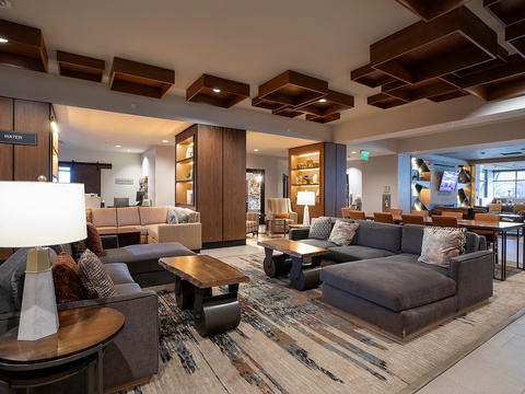 Sink into modern comfort in this stylish lobby lounge, where warm wood tones and plush seating create your perfect spot to unwind and connect.