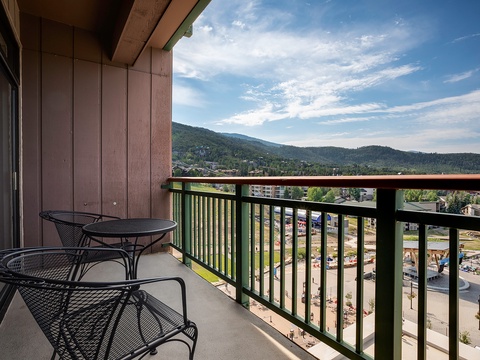 A private balcony overlooks a forested mountain landscape and a lively community aqua park, offering a scenic spot to relax with morning coffee or evening drinks.