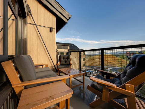 Unwind on your private balcony with comfortable lounge chairs, soaking in the open landscape views as the sun sets over the surrounding hills and valley.