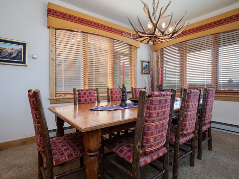 Gather around this rustic dining table and share memorable meals together beneath a striking antler chandelier while soaking in the mountain views through expansive windows.