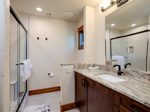 Your modern bathroom features elegant marble countertops, a spacious walk-in shower with glass enclosure, and warm wood accents that create a serene spa-like retreat for unwinding after your adventures.