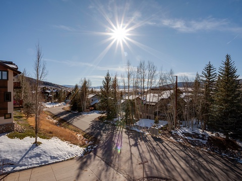 A sunlit mountain neighborhood showcasing surrounding homes, evergreens, and distant peaks during winter—part of the property's scenic location.