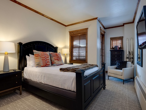 Your cozy bedroom retreat features elegant black furnishings, soft linens, warm lighting, and a comfortable seating area—perfect for unwinding after a day of mountain adventures.