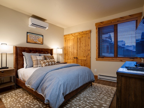 You'll rest easy in this inviting bedroom with soft linens, warm wood accents, and modern climate control. The peaceful mountain views through the window complete your cozy retreat.