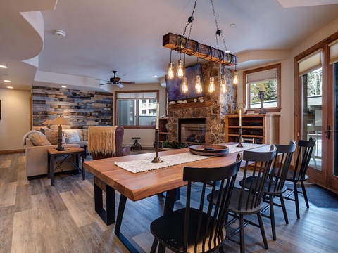 Gather around this stunning handcrafted table where rustic wood meets modern comfort. Natural light pours through expansive windows while the stone fireplace adds warmth to your mountain retreat.