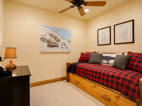 Sink into your cozy daybed adorned with warm plaid linens and mountain-inspired accents. The rustic wood frame and cabin artwork create your perfect alpine retreat.