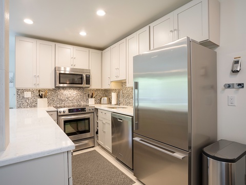 Step into your fully equipped kitchen with gleaming stainless steel appliances, crisp white cabinetry, and modern conveniences ready for preparing delicious meals during your stay.