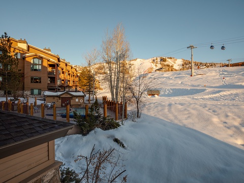 A snow-covered mountain resort with ski slopes and lift infrastructure, showcasing winter mountain accommodations bathed in warm golden-hour light.