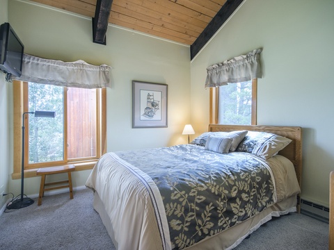 Unwind in your peaceful bedroom with a plush queen bed, vaulted wood ceilings, natural light from two windows, and a TV for your downtime.